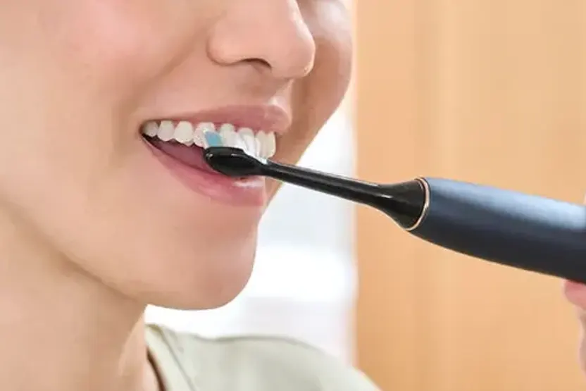 Mujer se cepilla los dientes con cepillo eléctrico